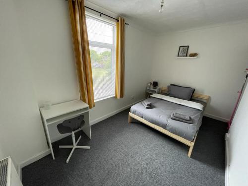Schlafzimmer mit einem Bett, einem Schreibtisch und einem Fenster in der Unterkunft Cheerful 2 bedroom house in Hindley