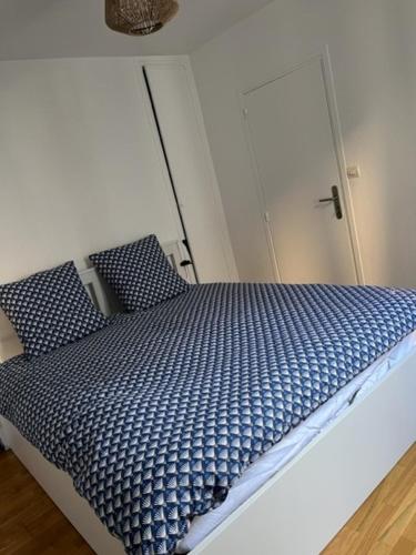 a bed with blue comforter and pillows in a room at Appartement hypercentre Fontainebleau in Fontainebleau
