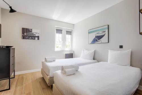 2 łóżka w pokoju z białymi ścianami w obiekcie Castel Saint Clair - Trois Pièces - Deauville Centre w mieście Deauville