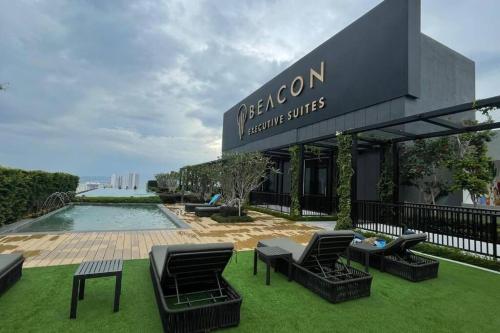 a building with chairs and a pool in the grass at Beacon Executive Suite at Georgetown for 10pax and 2 BED ROOM in George Town