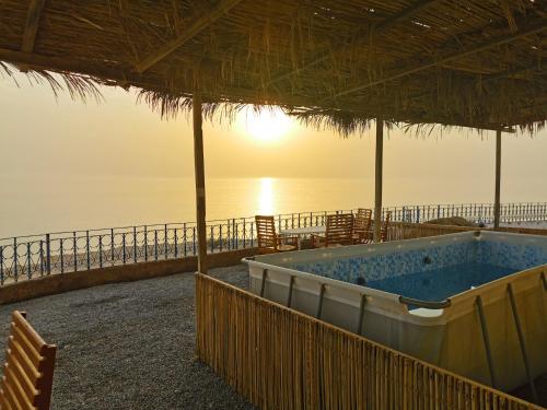 a hot tub on the beach next to the ocean at Wadi ashab chalets شاليهات وادي الشاب in Sur