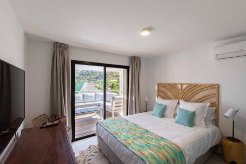 a bedroom with a bed with a view of a balcony at Villa Les Belles Vues de St Jean in Saint Barthelemy