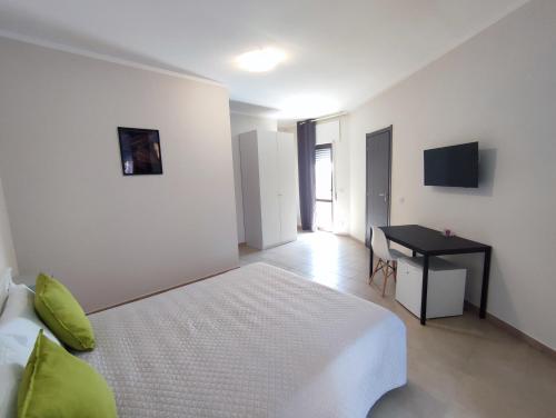 a white bedroom with a bed and a desk at Cristian Rooms in Avola