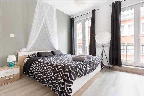 a bedroom with a black and white bed and a window at Apt B Boston, 25m2, Centre, Balcon 1 in Valenciennes