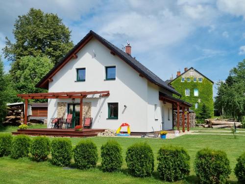 a white house with a playground in the yard at Dům a chatka pod Smrkem in Nové Město pod Smrkem