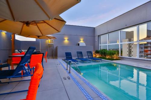 a swimming pool with chairs and an umbrella in a building at Hilton Garden Inn Santo Andre in Santo André