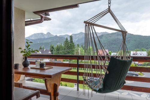 a hammock on a balcony with a table and a view at Pokoje Gościnne Maryniarczyk in Kościelisko