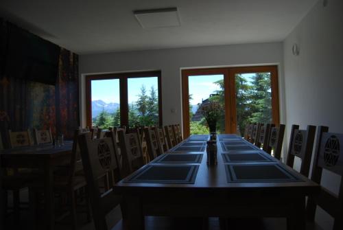 a room with a long table and chairs and windows at Willa Cisyna in Gliczarów