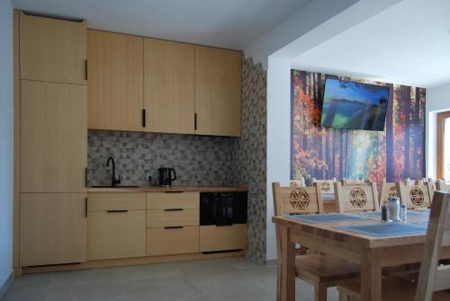 a kitchen with wooden cabinets and a table at Willa Cisyna in Gliczarów