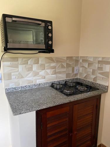 a microwave above a stove in a kitchen at Recanto da Floresta - Casa de campo em Secretário in Petrópolis