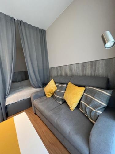 a living room with a gray couch with yellow pillows at Apartament Bastion Wałowa Gdańsk in Gdańsk