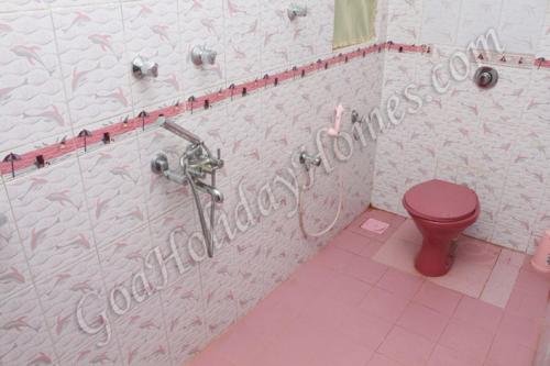 a bathroom with a pink toilet and a shower at Shalom Dream Home in Candolim