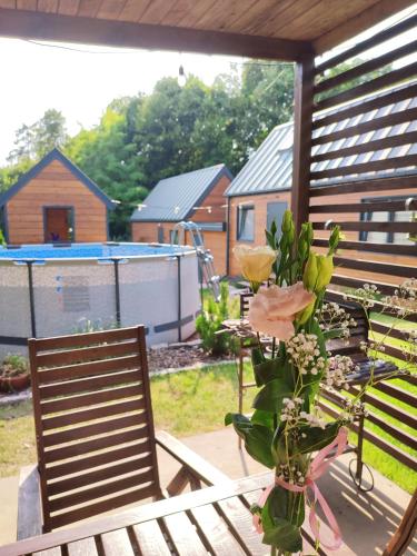 a vase of flowers sitting next to a chair on a patio at Lawendowo- sauna, basen, domki w ogrodzie i apartamenty w kamienicy in Sandomierz