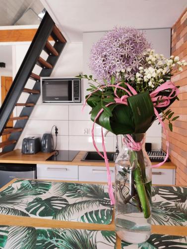 a vase with flowers on a table in a kitchen at Lawendowo- sauna, basen, domki w ogrodzie i apartamenty w kamienicy in Sandomierz