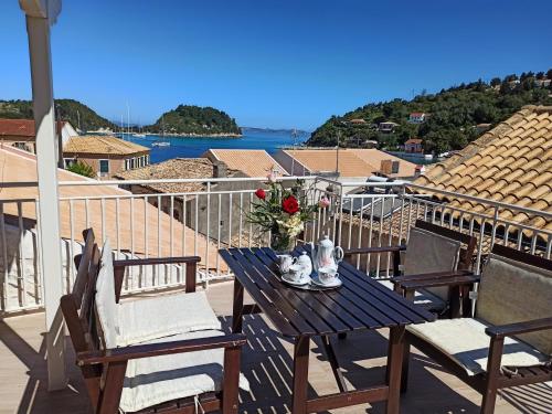 a blue table with a vase of flowers on a balcony at Dimitri's Seaview Studio - Lakka Paxos in Lákka