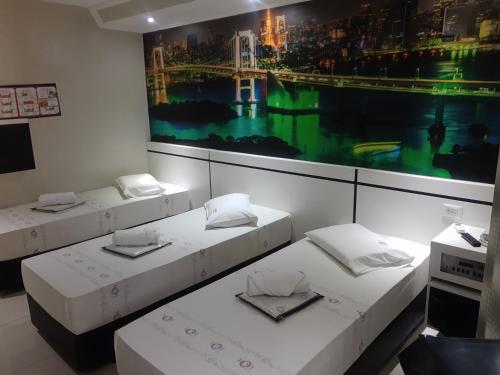 a room with three beds and a painting on the wall at Motel Fest (Adults Only) in Santo André