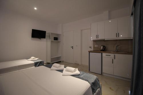 a white room with two beds and a kitchen at Vila Ori in Ksamil