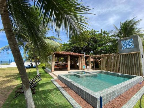 a swimming pool with a clock on a building at Morada da Praia - Porto de Pedras à Beira-Mar in Pôrto de Pedras