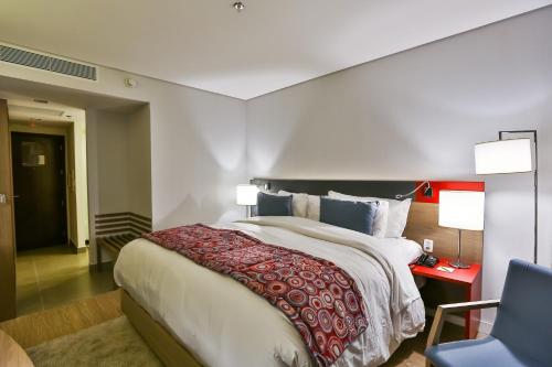 a bedroom with a large bed and a blue chair at Hilton Garden Inn Santo Andre in Santo André
