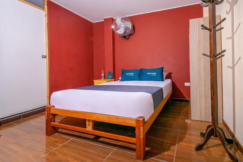 ein Schlafzimmer mit einem Bett in einer roten Wand in der Unterkunft Ayenda Muñoz in Ica