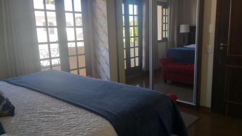 a bedroom with a bed and a red chair and windows at Pousada da Paz in Curitiba