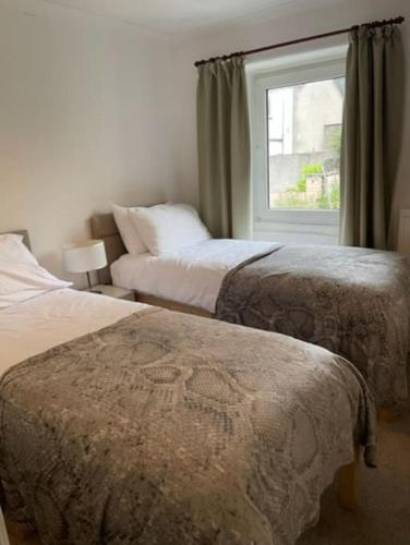 a bedroom with two beds and a window at Burlington Cottage - Ulverston, Lake District. in Ulverston