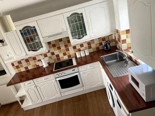 a kitchen with white cabinets and a sink at Burlington Cottage - Ulverston, Lake District. in Ulverston