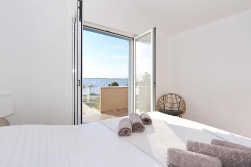 sypialnia z dużym białym łóżkiem i dużym oknem w obiekcie Beach front Holiday home Victoria in beautiful nature - by TA Leut Agency w mieście Zaton