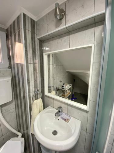 a bathroom with a sink and a toilet and a mirror at Apartmani Lazarevic Jagodina in Jagodina