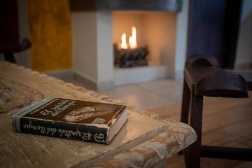 a book sitting on top of a bench with a fireplace at Casa Naré Adults Only in San Miguel de Allende