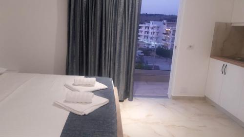 a room with a bed and a window with towels at Vila Ori in Ksamil