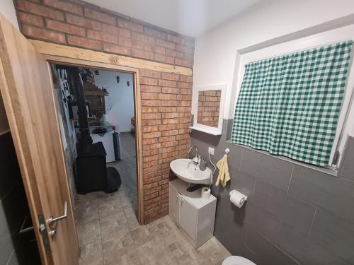 uma casa de banho com um lavatório e uma parede de tijolos em Kuća za odmor "Arija" em Zlobin