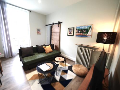 un salon avec un canapé vert et des chaises dans l'établissement L'AMIRAUTE - Design - Centre ville - Balcon, à Vichy