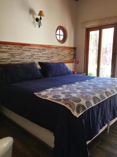 a bedroom with a bed with a blue comforter at Hostal Puritama in San Pedro de Atacama
