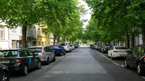 a row of cars parked on a street with trees at Flying Bed Apartment close to Prague Castle and Airport in Prague