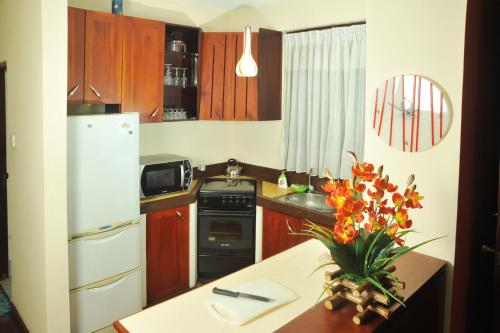 a kitchen with a white refrigerator and a table with flowers at Prestige Court Residencies in Mount Lavinia