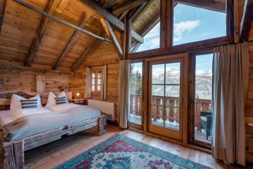 a bedroom in a log cabin with a bed and large windows at Landgut Moserhof in Penk