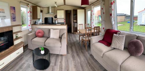 ein Wohnzimmer mit 2 Sofas und einer Küche in der Unterkunft Ferienhaus Nr916 Persdirekt am Wattenmeer mit Meerblick, hundefreundlich eingezäunt in Westerland