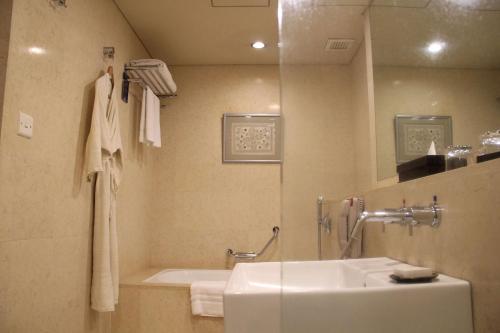 a bathroom with a sink and a tub and a mirror at Radisson Blu Dhaka Water Garden in Dhaka