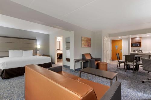 Best Western Plus McAllen Airport Hotel في ماكالين: فندق غرفه بسرير وصاله