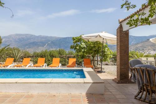 a swimming pool with orange chairs and an umbrella at Casa Rural Liviana, Piscina Barbacoa y preciosas vistas Málaga by AndaraHolidays in Cómpeta
