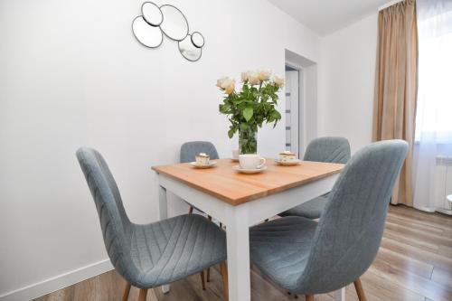 a dining room table with blue chairs and a vase of flowers at Apartamenty Majka in Zator