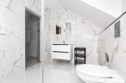 a white bathroom with a toilet and a shower at Osada Nord domki wypoczynkowe in Jastrzębia Góra