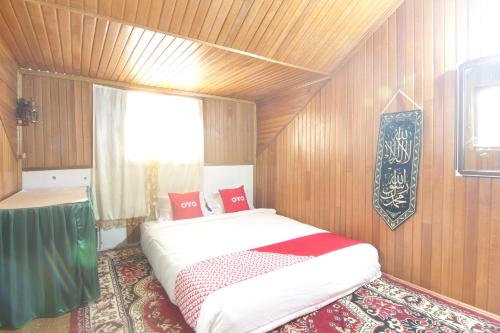 ein Schlafzimmer mit einem großen Bett in einem Zimmer mit Holzwänden in der Unterkunft New Bunga Sonsang Homestay Syariah in Tabing
