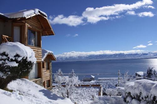 a cabin in the snow with a view of the water at Cabañas Chesa Engadina in San Carlos de Bariloche