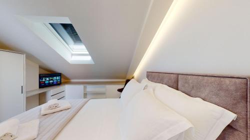 a bedroom with a large white bed with a skylight at Luxury Penthouse Adriatic Blue - On the beach in Tučepi