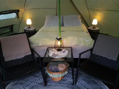 a tent with a bed and two chairs and a table at Leite Telt Camping in Lyngstad