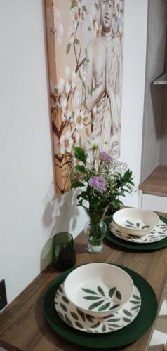 a table with two plates and a vase of flowers at ESTUDIO Jacuzzi SOL De JEREZ in Jerez de la Frontera