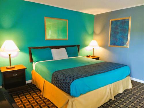 1 dormitorio con 1 cama con paredes azules y 2 lámparas en Grandview Plaza Inn, en Junction City