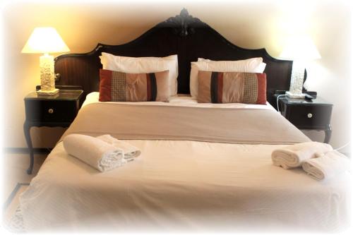1 dormitorio con 1 cama blanca grande y toallas. en Airport Lodge Guest House, en Kempton Park